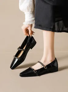 Dettaglio di ballerine Mary Jane nere a punta con finitura lucida e catene in metallo oro