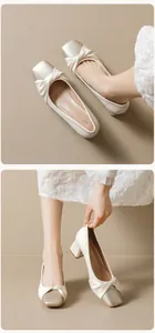Detail of satin cream mid-heel shoes with silver toe cap and knot decoration