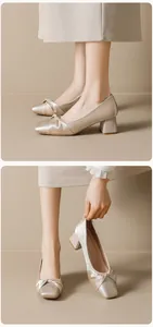 Detailed close-up of champagne satin block heel pumps with elegant bow and square toe