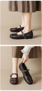 Dettaglio di scarpe Mary Jane in pelle marrone scuro con decorazioni brogue e fibbia