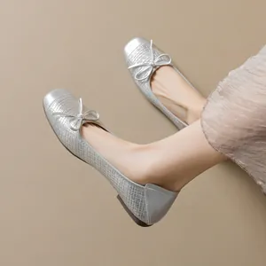 Bailarinas tejidas plateadas con punta cuadrada y lazo llevadas por modelo sobre gris