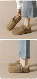 Detailed close-up of brown suede mule slippers featuring vintage square toes and metal buckles