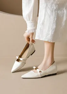 Detail von cremefarbenem Mary Jane Ballerina mit goldener Vintage-Blumenschnalle am Riemen