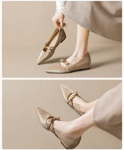 Makroansicht von beigen Satin-Mary-Janes mit spitzer Kappe und goldener Rosenschnalle