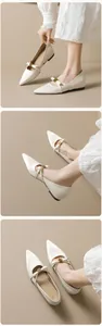 Nahaufnahme von cremefarbenen Mary Jane Ballerinas mit Schleife und goldener Schnalle