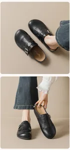 Detail showing black matte leather mules with tassel decor and perforated wingtip patterns