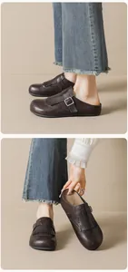 Close-up of retro brown leather mules with fringe details and buckle strap accents