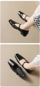 Detail of black square toe Mary Jane flats with delicate metal buckle strap on beige floor