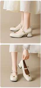Detailed macro view showing the cream Mary Jane shoe with gold vintage floral buckle