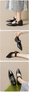 Detail of black pointed Mary Jane shoe featuring a gold heart buckle and chunky heel