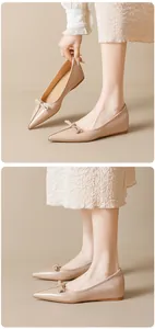Detailed view of beige pointed toe flats with bow accent and glossy leather texture