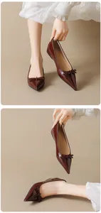 Detail of dark red patent leather pointed flats with a delicate bow and glossy finish