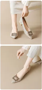 Close-up of champagne pointed-toe pumps with sparkling rhinestone buckle and textured fabric