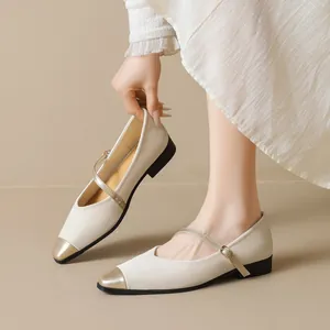 French-style beige Mary Jane flats with gold-tone cap toes and buckle straps