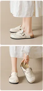 Close-up of beige vintage brogue mule featuring floral carvings and a metal buckle