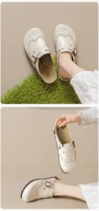 Detail view of beige Birkenstock style mule with brogue carved patterns and metal buckle