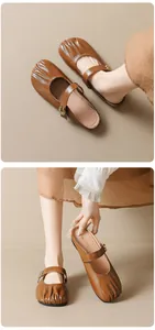 Detailed close-up of brown Mary Jane mules with pleated toe and golden buckle strap