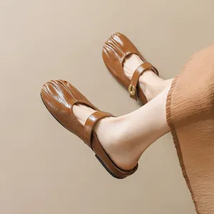 Elegant brown pleated Mary Jane mule shoes with vintage strap and flat sole on model