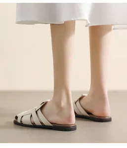 Close-up of beige woven leather flat sandals with crossover straps and brown rubber sole