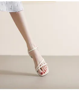 Detalle de sandalias planas crema con tiras finas cruzadas y hebilla de pequeña perla