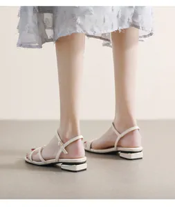 Detalle de sandalias planas beige con tiras finas y elegante adorno metálico dorado en el tacón