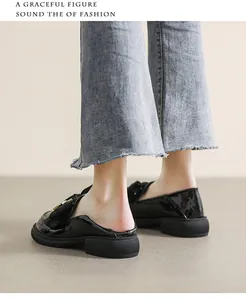 Primer plano de mocasines en charol negro con hebilla de metal y suela gruesa
