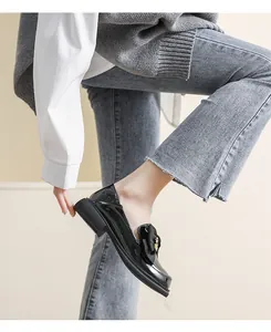 Detalle de mocasines de charol negro con lazo de cinta y hebilla dorada elegante