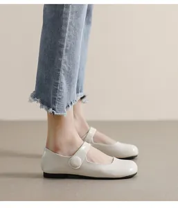 Detail of cream Mary Jane flat shoes with round toe and strap worn with denim jeans