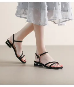 Primer plano de sandalias negras minimalistas con tiras finas y tacón cuadrado