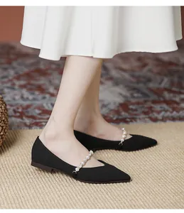 Close-up of black pointed flat shoes with textured knit surface and pearl strap detail