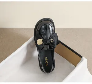 Mocasines de charol negro con lazos de satén grandes y hebillas doradas en vista superior