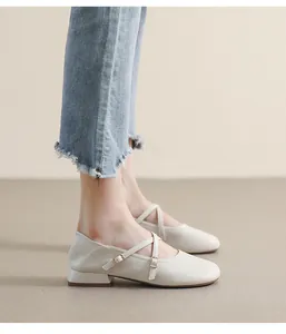 Seitenansicht cremefarbener Mary Janes mit Kreuzriemen und Metallschnallen an einem Model