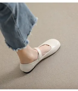 Close-up of beige leather Mary Jane flat shoes with buckle strap on feet from side view