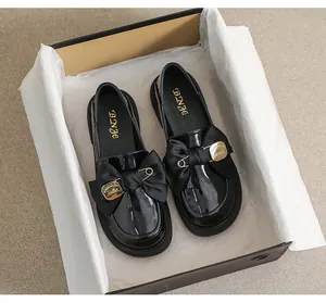 Vista superior de mocasines de charol negro con plataforma, lazo y detalles dorados