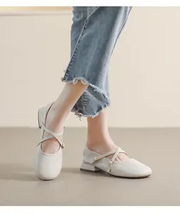 Detailaufnahme von cremefarbenen Mary Janes mit Kreuzriemen und goldenen Schnallen