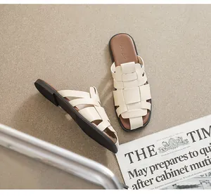 Macro detail of retro woven leather flat mules with cream straps and brown sole