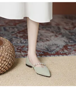 Detail of light green pointed-toe flats with elegant pearl strap and woven texture