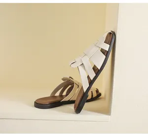 Detail of woven leather straps on retro cream Roman flat sandals in minimalist niche