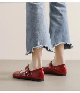 Detail of red leather Mary Jane flat shoes with glossy finish and round toe on denim jeans