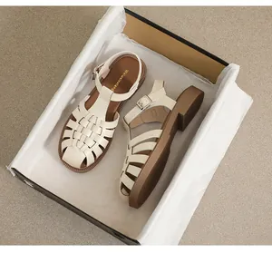Draufsicht auf cremefarbene Flechtsandalen im Schuhkarton mit weißem Staubpapier