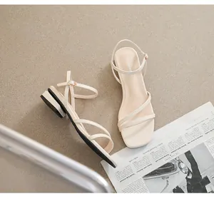 Detalle de sandalias crema con punta cuadrada, tiras finas y hebilla de metal ajustable