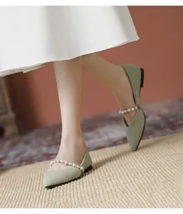 Detail of light green pointed flat shoes with elegant pearl strap and textured fabric
