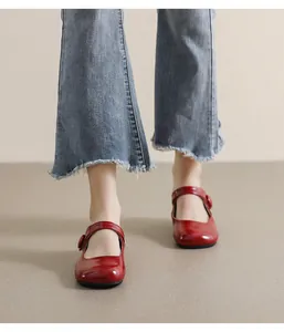 Close-up of red patent leather Mary Jane shoes with round toe and buckle strap detail