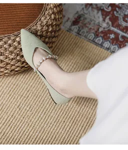 Detail of green pointed-toe flats featuring soft knit texture and pearl strap design