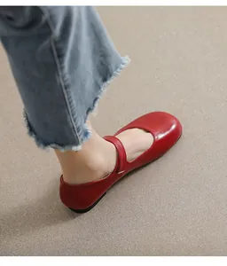 Detail of red Mary Jane shoes with round toe and glossy finish on light floor