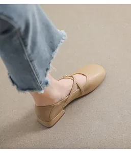 Detail von beige Mary Jane Schuhen mit gekreuzten Riemen und goldener Metallschnalle