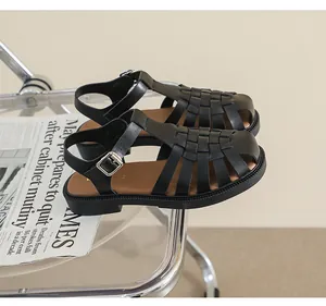 Detailansicht schwarzer geflochtener Leder-Fischersandalen auf einem modernen Stuhl