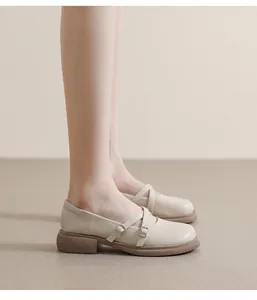 Side view of beige platform Mary Jane shoes with cross straps and metal buckles on a model