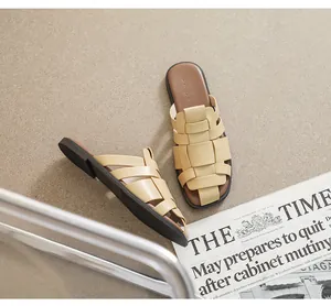 Detailed view of beige woven leather flat sandals on minimalist textured background
