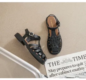 Detail der schwarzen geflochtenen Gladiatorensandalen mit Metallschnalle und dicker Sohle